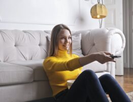happy young relaxed woman watching tv at home