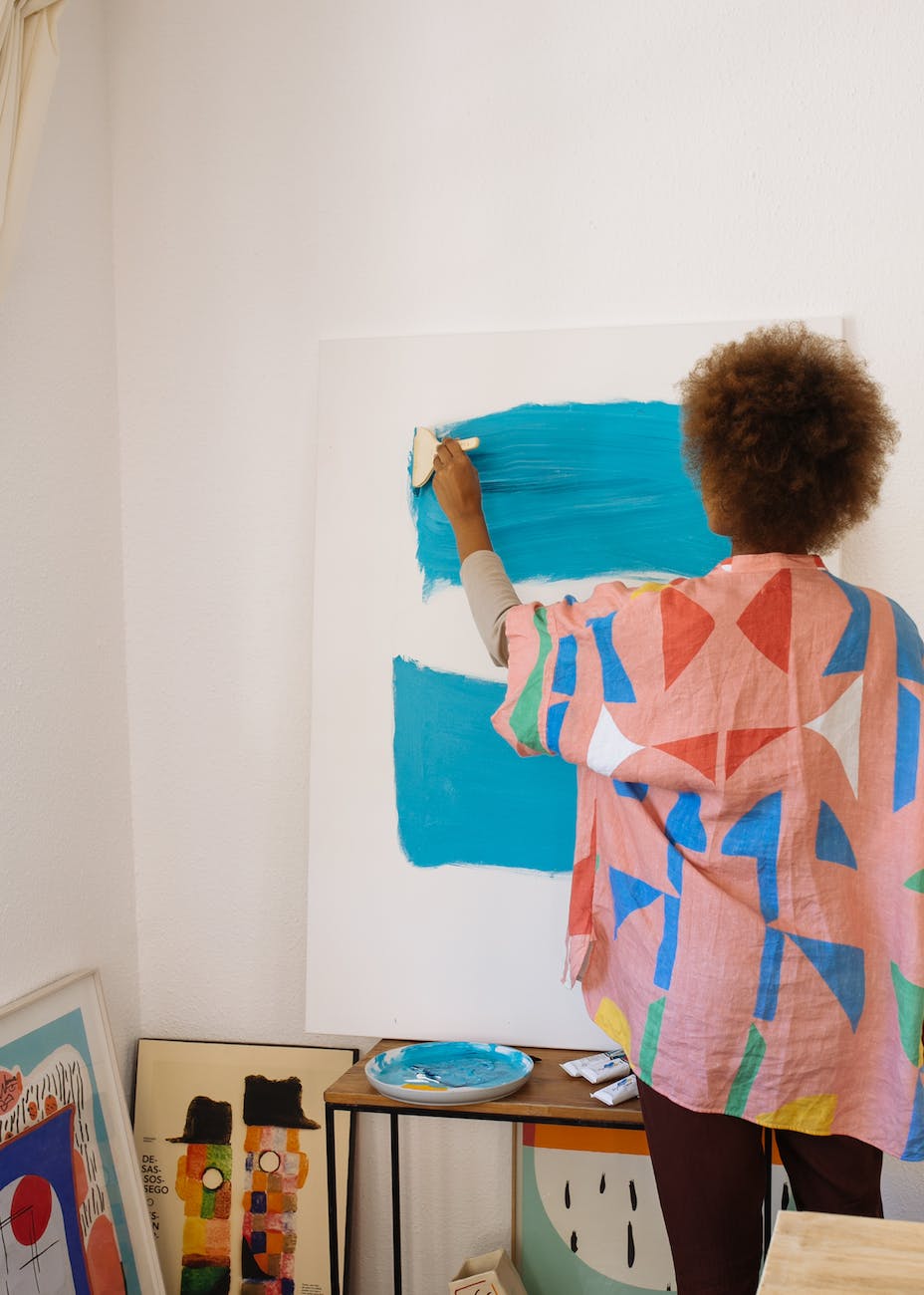photo of woman painting with blue paint