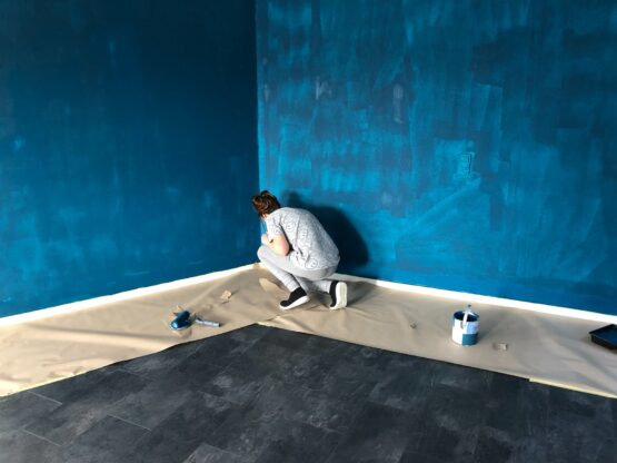 woman in gray shirt and gray pants painting the walls