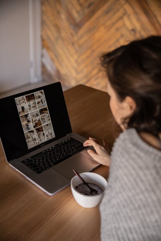 crop young woman using laptop in cafe and eating breakfast