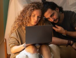 young couple using laptop while sitting on floor in living room