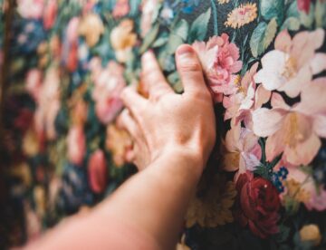 crop person touching colorful floral wallpaper