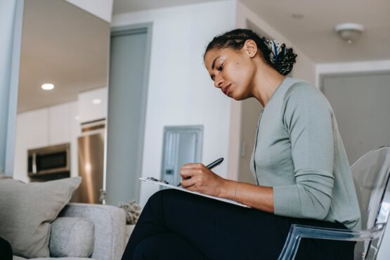 concentrated ethnic female interviewer or psychotherapist taking notes in clipboard