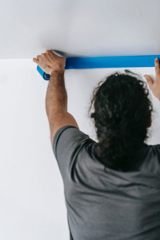 man putting tape on wall